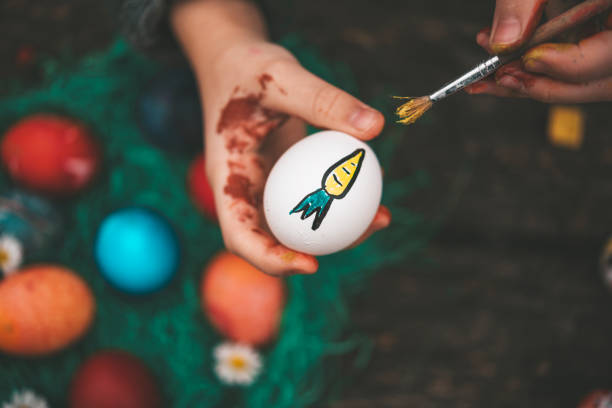 Overhead view on Childs hand painting easter eggs on old wooden table