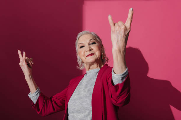 istock Fashionable old lady making rock and roll sign in studio 1138139651