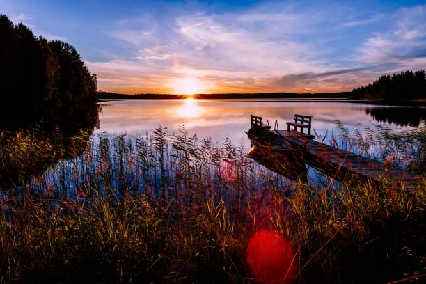 деревянный пирс с рыбацкой лодкой на закате на озере в финляндии - romance lake chair sunset стоковые фото и изображения
