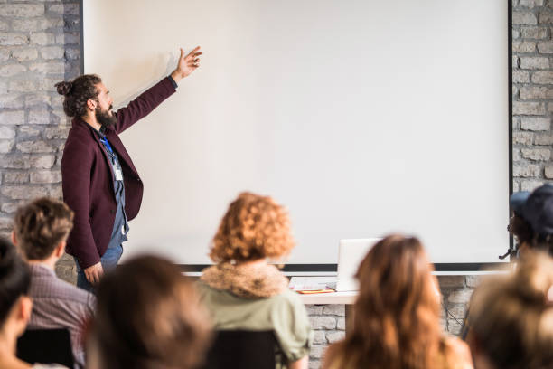 empreendedor masculino novo que educa seus colegas em uma apresentação no escritório. - presenter young adult women marketing - fotografias e filmes do acervo