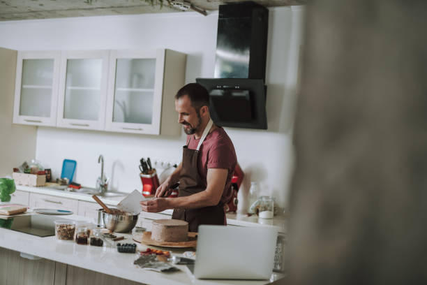 istock Positive man smiling while smoothing cream on the cake 1138150441