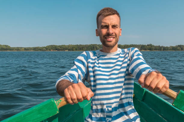 istock Young man rowing boat through lake in summertime 1138154090