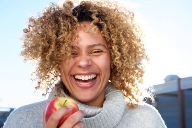 Close up healthy young african american woman holding apple Close up portrait of healthy young african american woman holding apple plus size woman fashion laughing stock pictures, royalty-free photos & images
