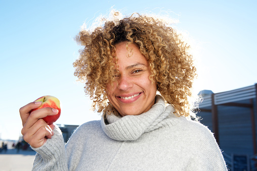 Close up portrait of beautiful african american woman holding apple