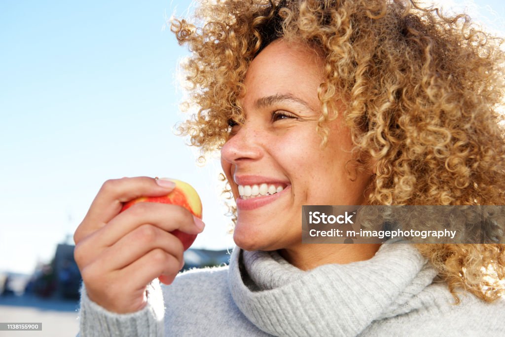 side portrait of healthy young african american woman holding apple Close up side portrait of healthy young african american woman holding apple Eating Stock Photo