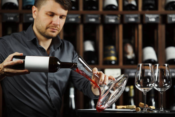 istock Serious sommelier pouring red wine in decanter 1138157092