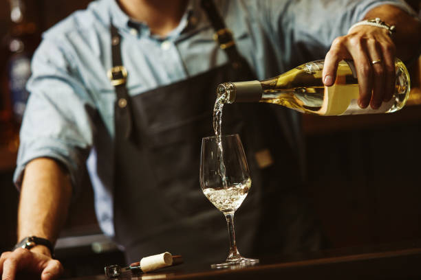 sommelier masculino que vierte vino blanco en una viticultura de tallo largo. - wine pouring wineglass white wine fotografías e imágenes de stock
