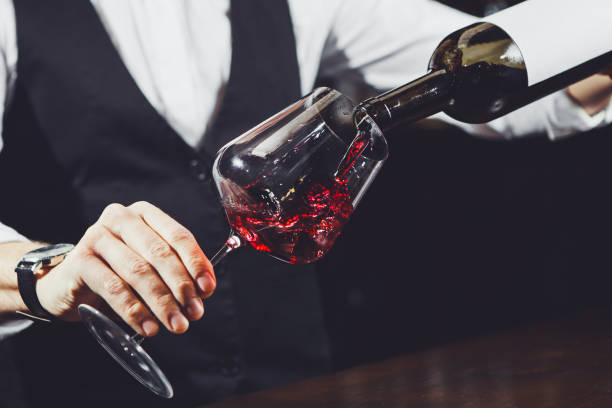 Close up shot of sommelier pouring red wine from bottle in glass Close up shot of sommelier male pouring red wine from bottle having label into glass on angle, alcoholic beverage degustation, bar counter sommelier photos stock pictures, royalty-free photos & images