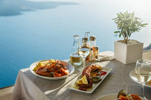 Dinner for two with fish dishes and white wine, a table on the background of the sea