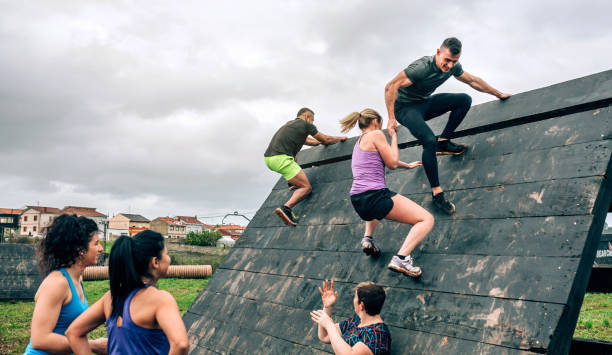 participants in obstacle course climbing pyramid obstacle - team effort imagens e fotografias de stock