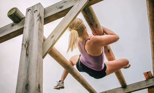 Female participant in a obstacle course doing weaver obstacle
