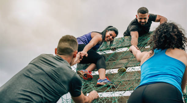 Participants in obstacle course climbing net Group of participants in an obstacle course climbing a net hurdle stock pictures, royalty-free photos & images