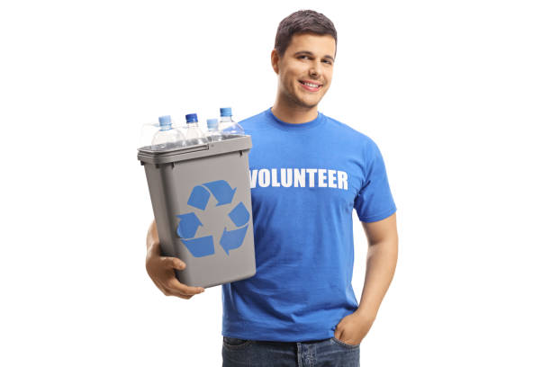 Multi-ethnic group of young adults collaborate to organize a recycling campaign.  African descent man foreground with recycling bin. Female volunteer holds \