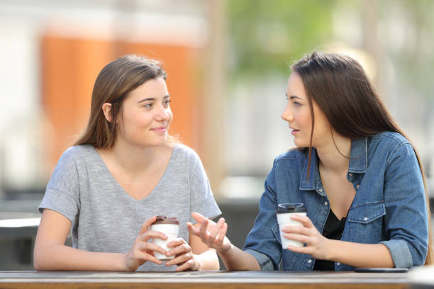 due amici che parlano in un parco bevendo caffè - amicizia tra uomini foto e immagini stock