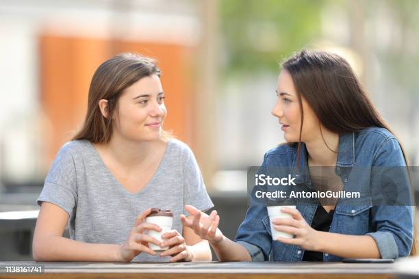 Due Amici Che Parlano In Un Parco Bevendo Caffè - Fotografie stock e altre immagini di Scambio d'idee - Scambio d'idee, Parlare, Due persone