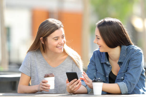istock Two friends talking about phone content in a park 1138161791