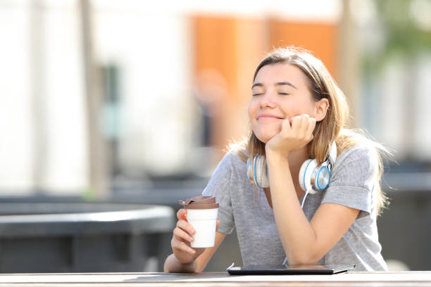 jeune fille heureuse retenant le café dans un parc - fresh coffee audio photos et images de collection