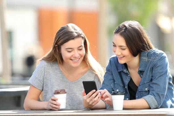 istock Two friends checking smart phone online content in a park 1138161918