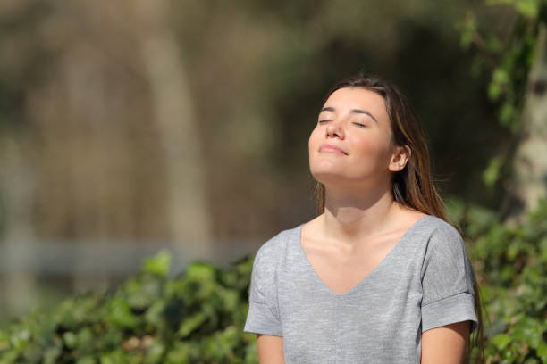 menina relaxed que respira o ar fresco em um parque um dia ensolarado - inhaling breathing exercise one person relaxation - fotografias e filmes do acervo