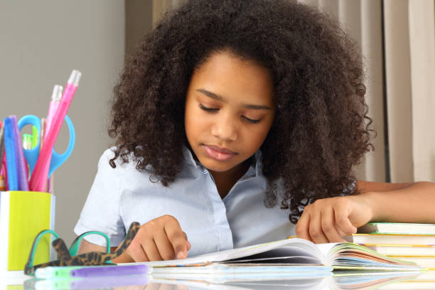 istock dark-skinned schoolgirl reading a book doing homework 1138165078