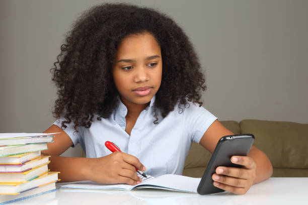 ciemnoskóra dziewczyna ze smartfonem odrabia pracę domową - homework teenager mobile phone school zdjęcia i obrazy z banku zdjęć