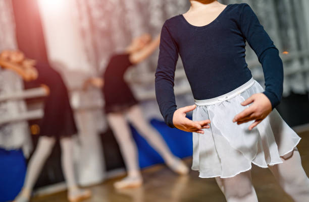 pequeña bailarina de pie en pose con sus manos sobre un fondo difuminado con dos bailarinas. - ballet dress studio shot costume fotografías e imágenes de stock