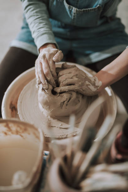 istock Young lady kneading and shaping clay on pottery wheel 1138166724