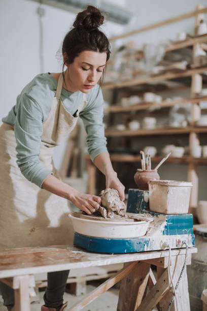 istock Attractive young lady in apron working on pottery wheel 1138166733