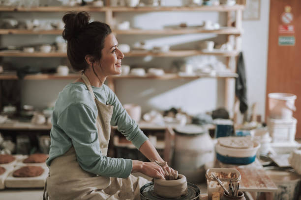 istock Joyful young lady in apron working on pottery wheel 1138166734