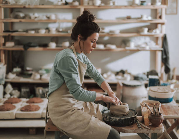 istock Charming young lady in apron working on pottery wheel 1138166737