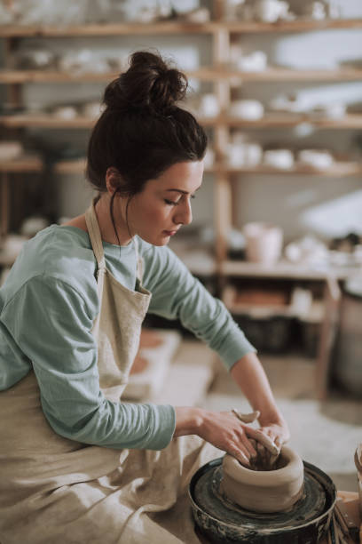 istock Serious young lady in apron working on pottery wheel 1138166738