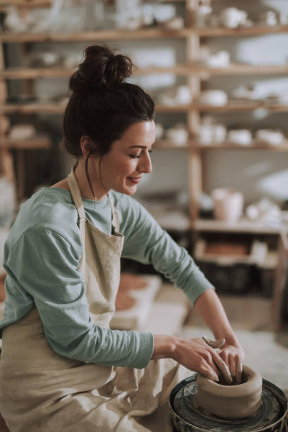 istock Joyful young lady in apron working on pottery wheel 1138166740