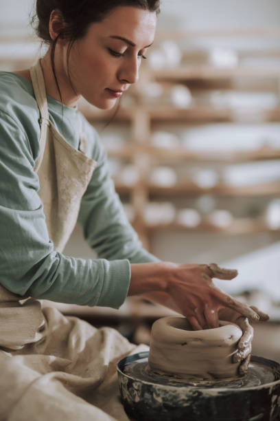 istock Beautiful brunette lady in apron working on pottery wheel 1138166741