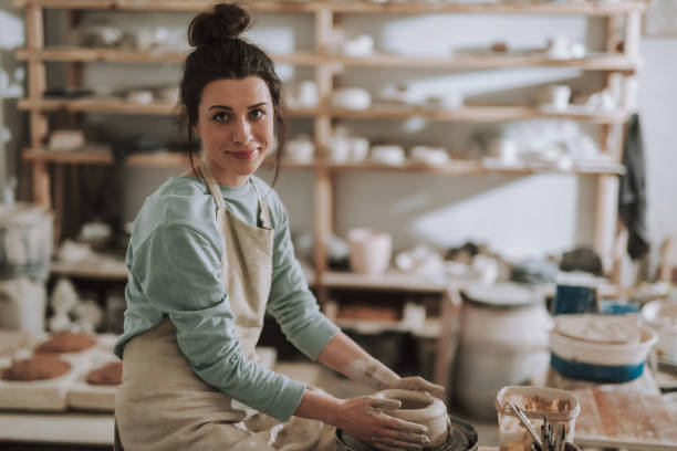 istock Joyful young woman in apron working on pottery wheel 1138166742
