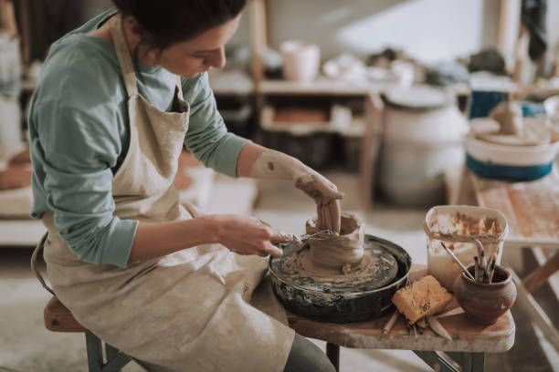 istock Female ceramic artist using sculpture scraper knife while making clay pot 1138166753