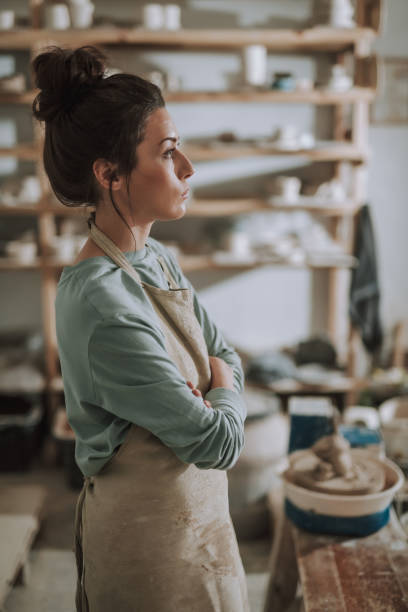 istock Attractive young woman in apron standing in pottery workshop 1138167269
