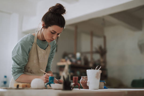 istock Beautiful young woman in apron working in pottery workshop 1138167277