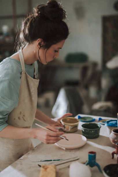 istock Charming young woman in apron working in pottery workshop 1138167279