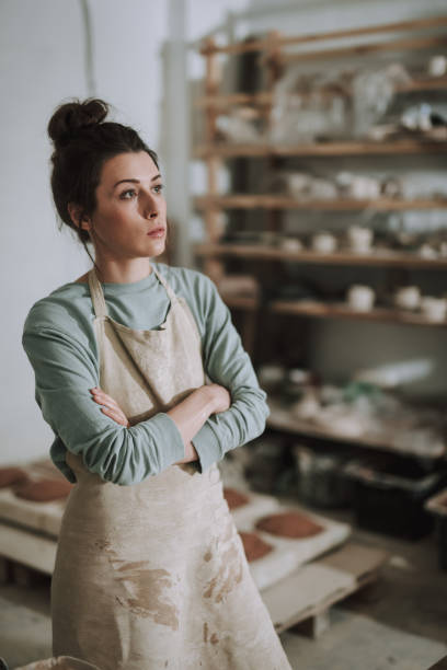 istock Beautiful young woman in apron standing in pottery workshop 1138167280