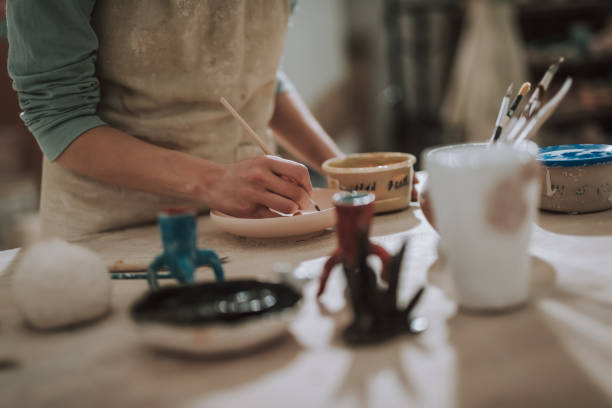 istock Female ceramic artic in apron painting pottery at workshop 1138167287