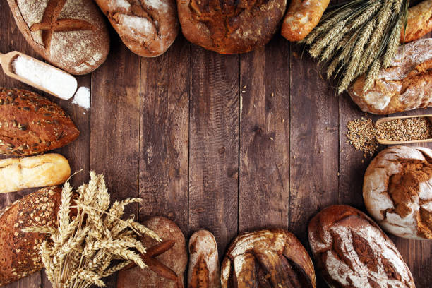 istock Different kinds of bread and bread rolls on board from above. Kitchen or bakery 1138169212