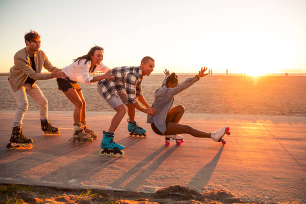 friends roller skating on the boardwalk in venice beach - santa monica promenade - los angeles, usa - santa monica venice beach california santa monica beach imagens e fotografias de stock