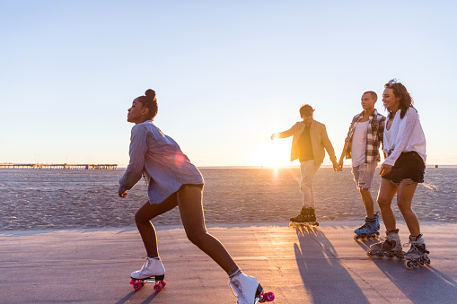 Friends roller skating on the boardwalk in Venice Beach - Santa Monica promenade - Los Angeles, USA