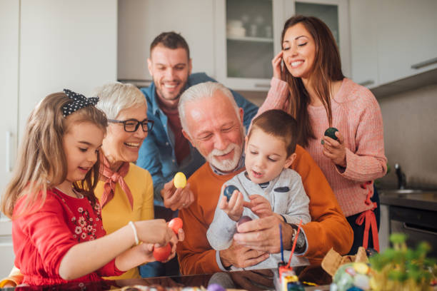 mehrgenerationenfamilie hält ostereier und lächelt - multi generation family stock-fotos und bilder