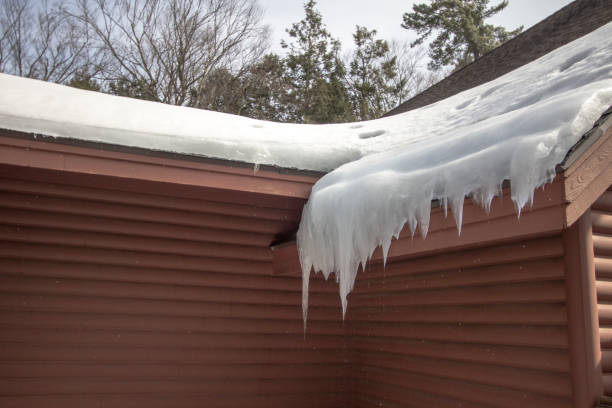 Icicles Hang From Ice Dam On Home Roof With Water Dripping Icicles on a roof with water dripping from below on home exterior. dam stock pictures, royalty-free photos & images