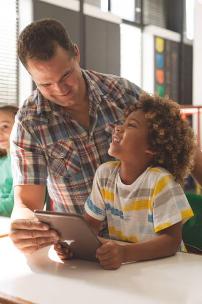 istock Surface level view of a teacher interacting with a school boy over a digital tablet 1138174455