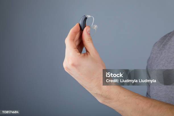 Holding Small Black Hearing Aid Stock Photo - Download Image Now - Hearing Aid, Holding, Small