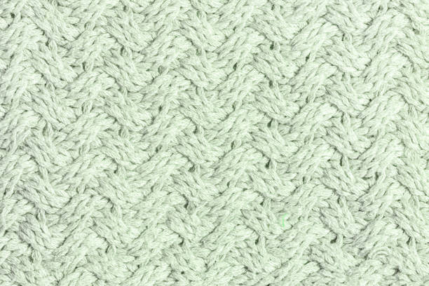 istock Wool weave. Knitted texture with an unusual pattern close-up. Light gray-green empty background for layouts. 1138175691