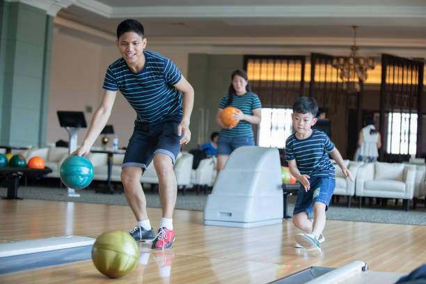 Father teaching son and family play bowling at bowling club on relax time stock photo