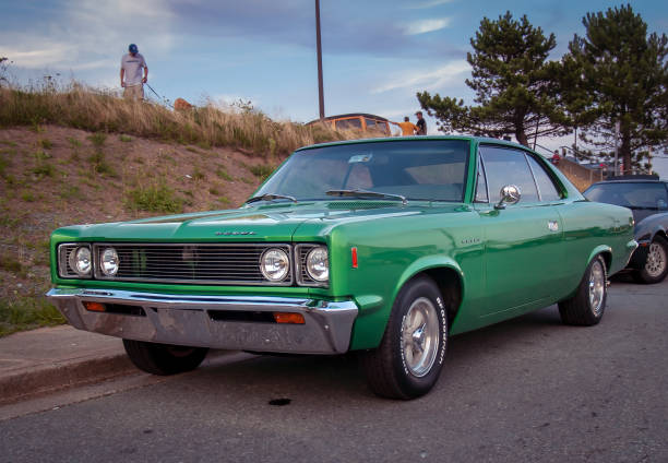 1969 AMC Rebel Dartmouth, Nova Scotia Canada., August 20, 2009: 1969 AMC Rebel muscle car at A&W summer Thursday weekly cruise-in at Woodside Ferry Terminal. In the background a man walks his dog and two men chat near a classic car. 1969 stock pictures, royalty-free photos & images